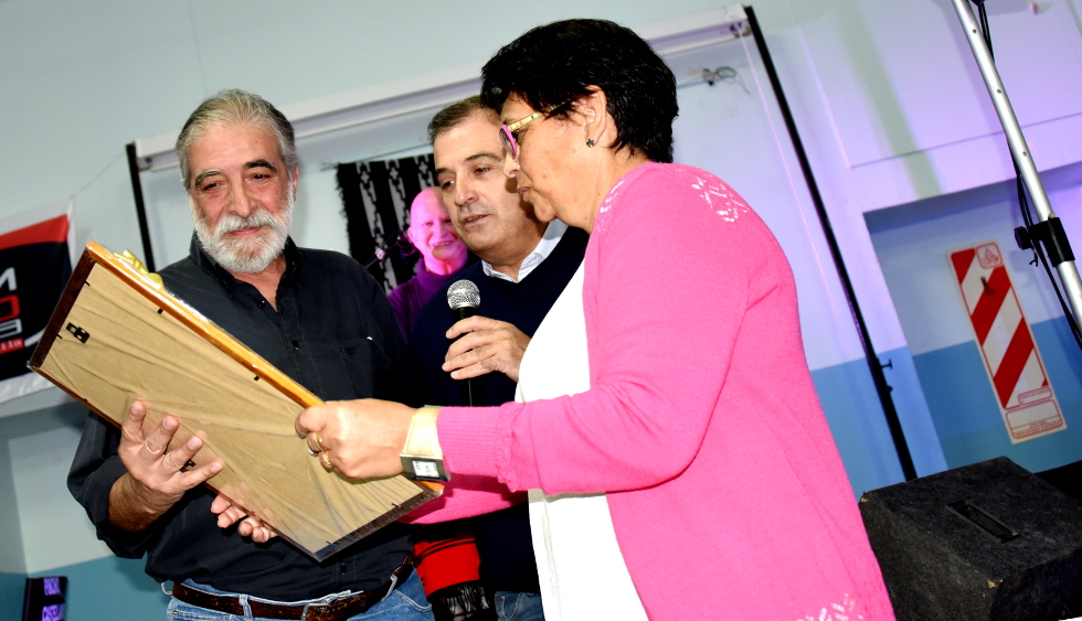 El vicegobernador Pedro Pesatti y la coordinadora Sandra Calvo entregan una imagen del escudo rionegrino al poeta salteño Juan Carlos Fiorillo.